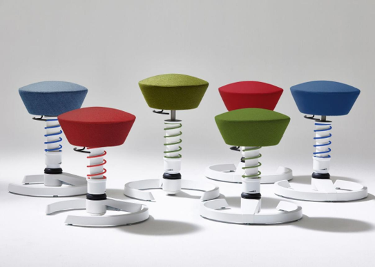 Group of colorful cushioned stools with coiled springs on white bases in a studio setting, arranged in a semicircle.